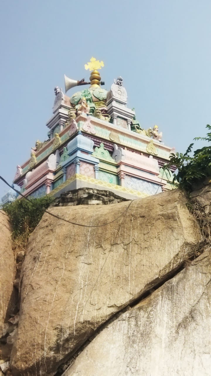 The painted vimanam of the temple rising above the granite hillock